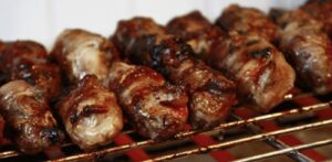 Gnummareddi, small rolls of lamb offal, grilling over coals