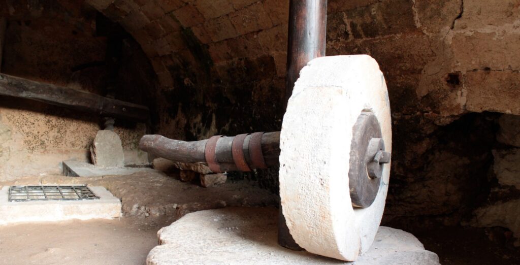 The large stone millstone of an underground olive mill in the Salento, with the wooden shaft that animals used to turn