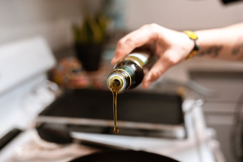 A thin stream of extra virgin olive oil poured from a dark glass bottle