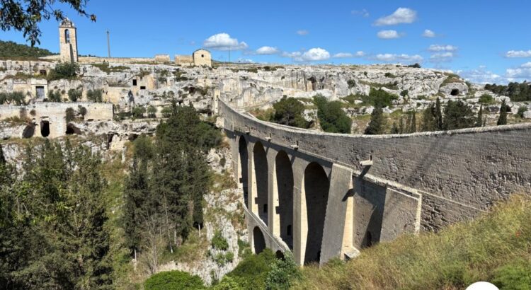 The aqueduct bridge of Gravina in Puglia over the ravine, with the old town and the rock churches behind