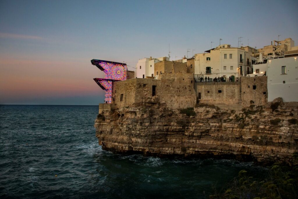 The Red Bull Cliff Diving platforms dressed in Salento luminarie on the cliff at Polignano a Mare at sunset