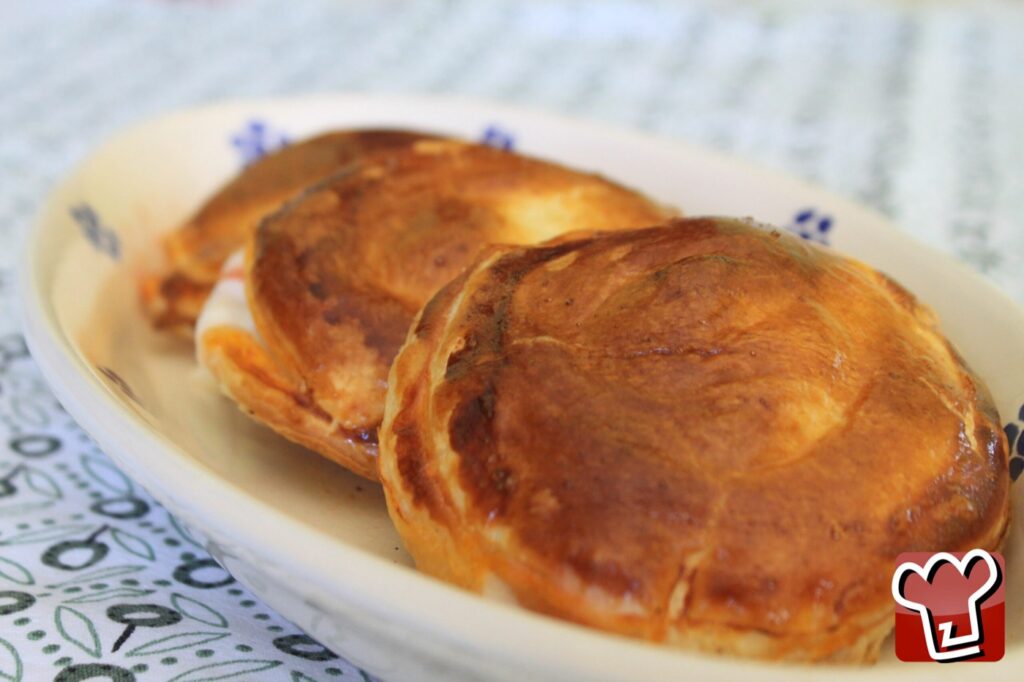 Three golden rustici leccesi, rounds of puff pastry, on a white plate